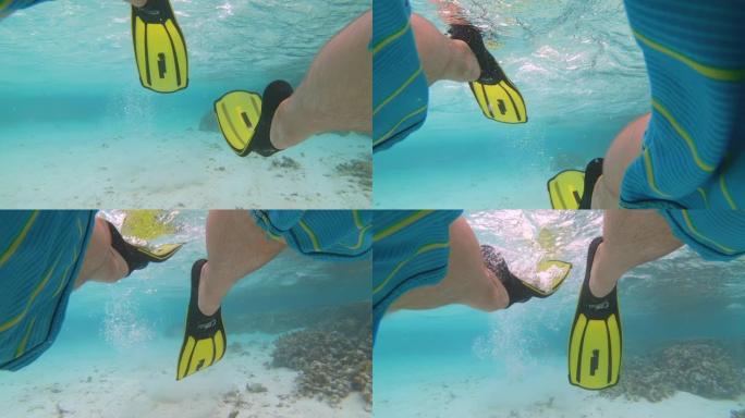 水下: 活跃的男性游客穿着脚蹼在海洋中浮潜。