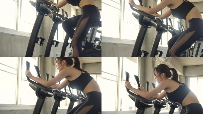 固定自行车上有吸引力的亚洲女性在健身房锻炼。慢动作。医疗保健、运动和运动概念。