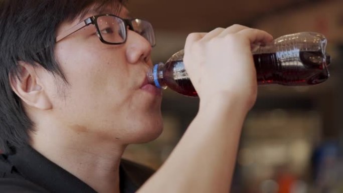 慢动作亚洲男子从瓶子里喝苏打水