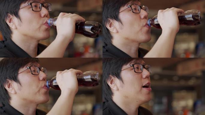 慢动作亚洲男子从瓶子里喝苏打水