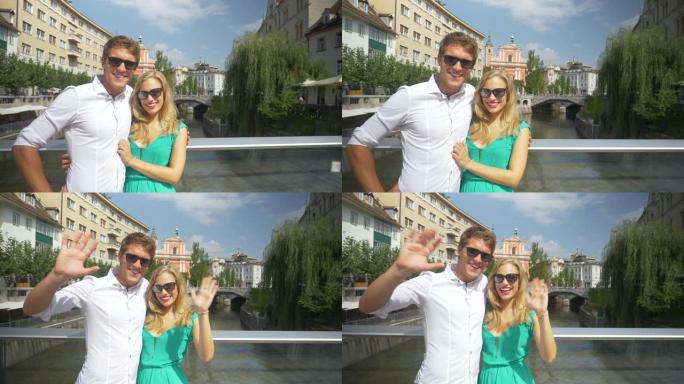 慢动作: 年轻的旅游夫妇站在桥上，对着镜头挥手。
