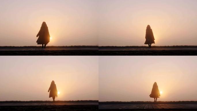 后视背景拍摄的快乐旅游女人与相机走到惊人的粉红色雾日落全景慢动作。