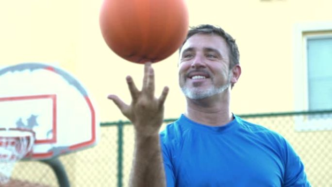 成熟的西班牙裔男子在指尖上平衡篮球