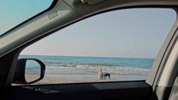 女士在意大利普利亚 (Apulia) 车外阳光明媚的海滩上与狗在一起的女人