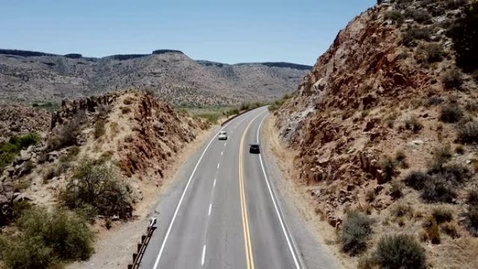 美国亚利桑那州夏季度假时，无人机跟随小型货车沿着雄伟的沙漠岩石山丘行驶。公路旅行概念。