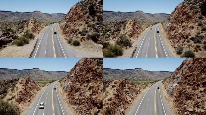 美国亚利桑那州夏季度假时，无人机跟随小型货车沿着雄伟的沙漠岩石山丘行驶。公路旅行概念。