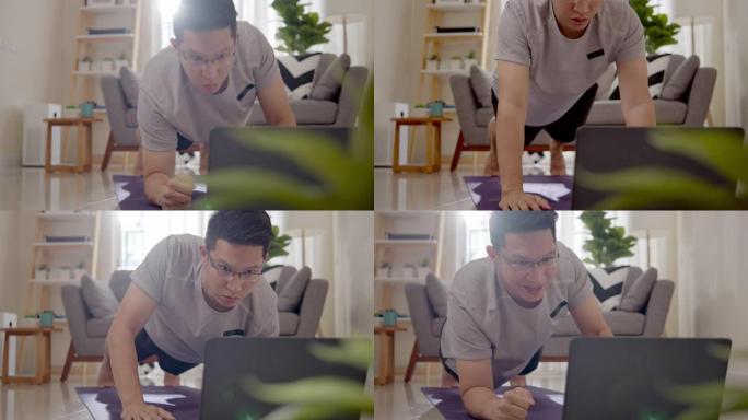 亚洲男子在家里的客厅做肘板上下运动，通过笔记本电脑在线观看直播或视频教程。检疫期间的活动和社会距离新
