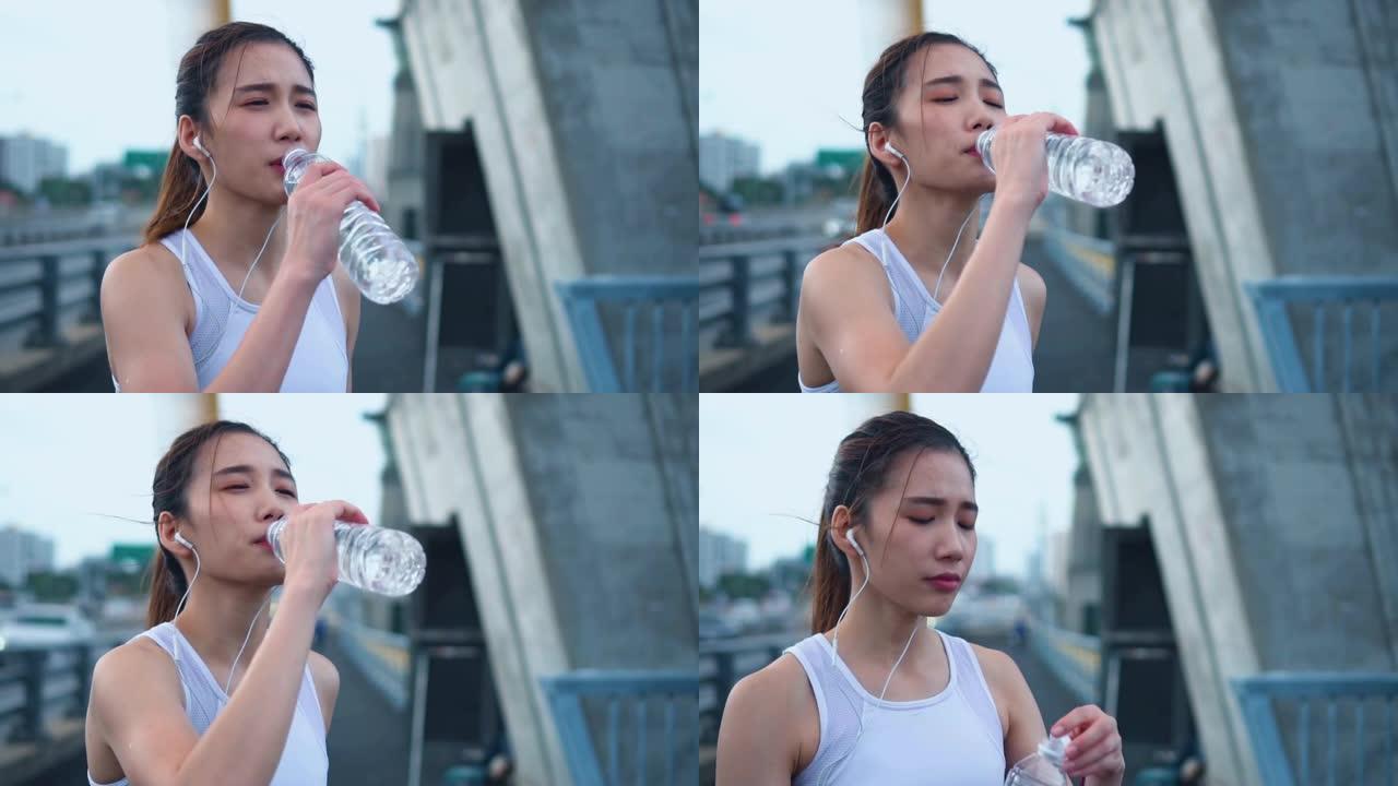年轻的亚洲运动员女子跑步后喝水，慢动作
