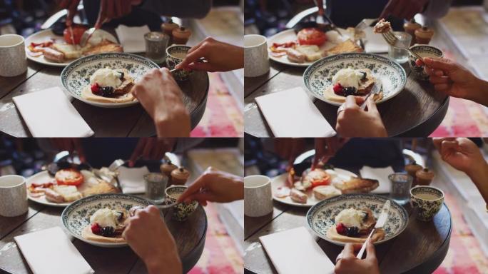 坐在传统英国度假酒店餐桌旁的情侣特写，吃煮熟的早餐和水果煎饼