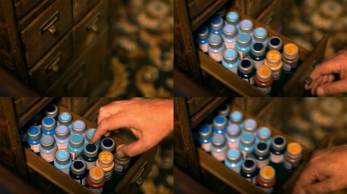 男性手打开一个装有不同油漆罐的木制抽屉。