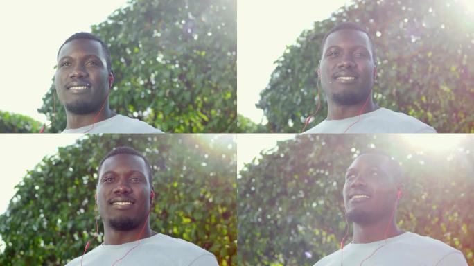 戴着耳机的非洲运动员在户外相机微笑