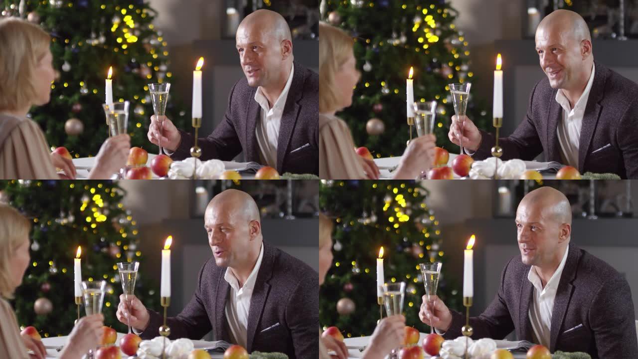英俊的白人男子在圣诞节晚宴上为妻子敬酒