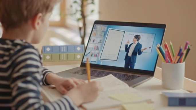 聪明的小男孩使用笔记本电脑与老师进行视频通话。屏幕显示在线讲座，老师从教室讲解主题。电子教育远程学习