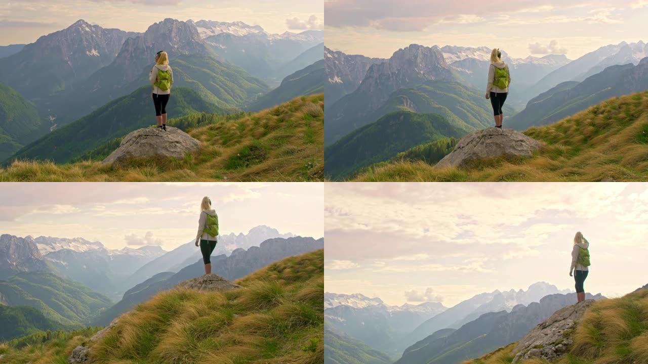 WS女徒步旅行者在岩石上俯瞰阳光明媚，雄伟，风景优美的山景。