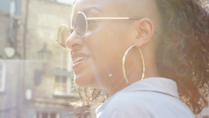 时尚的年轻黑人女子戴着墨镜在街上聊天，特写，侧视，镜头耀斑