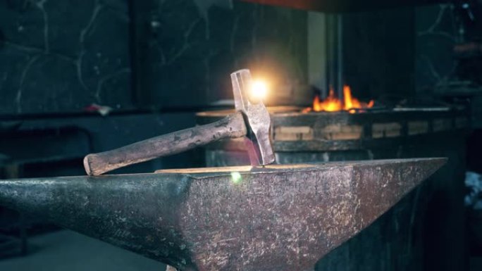 铁砧上的金属锤在锻炉的火背景上。