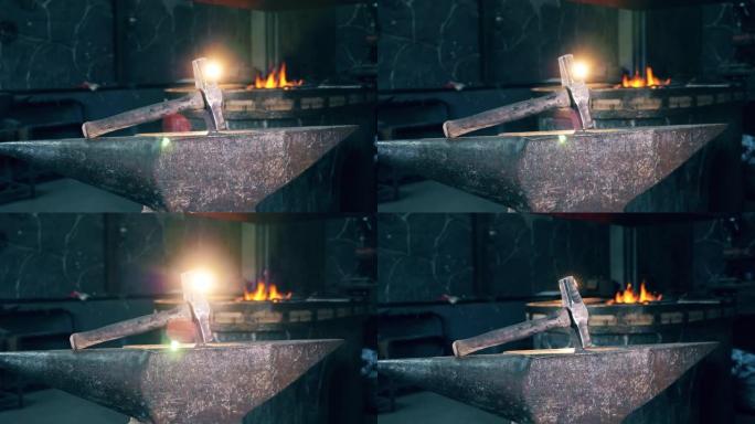 铁砧上的金属锤在锻炉的火背景上。