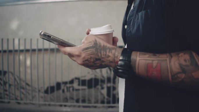时髦的人使用智能手机，在城市里拿着一杯咖啡。