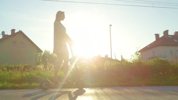 复制空间: 年轻女子在日落时骑着电动踏板车穿过郊区。