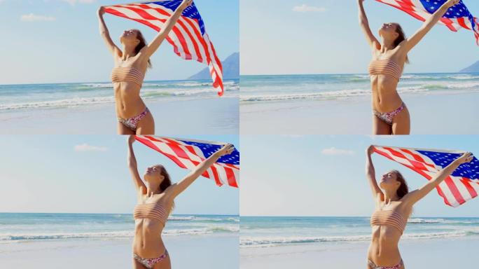 在海滩上手持美国国旗的年轻白人妇女的前视图4k