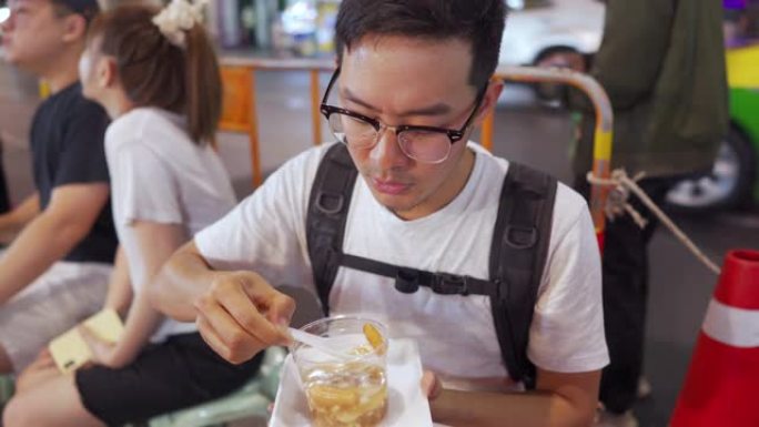 男人吃泰式甜点，在当地街头小吃中加入热姜糖浆的软豆腐