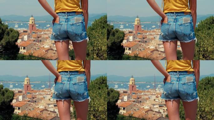 年轻女子穿着牛仔短裤，背景为圣特罗佩老城