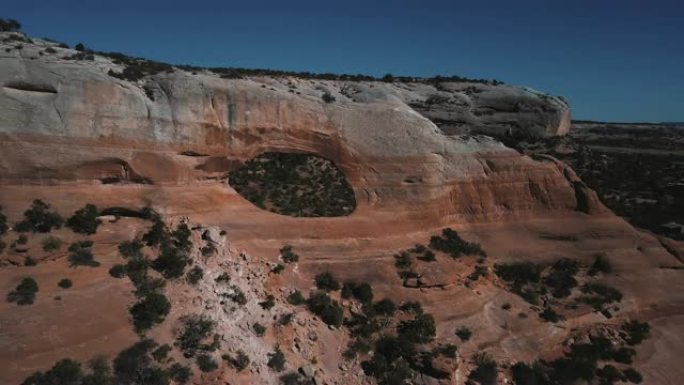 无人机飞离站在阳光明媚的亚利桑那山国家公园著名拱门岩层的旅游夫妇。