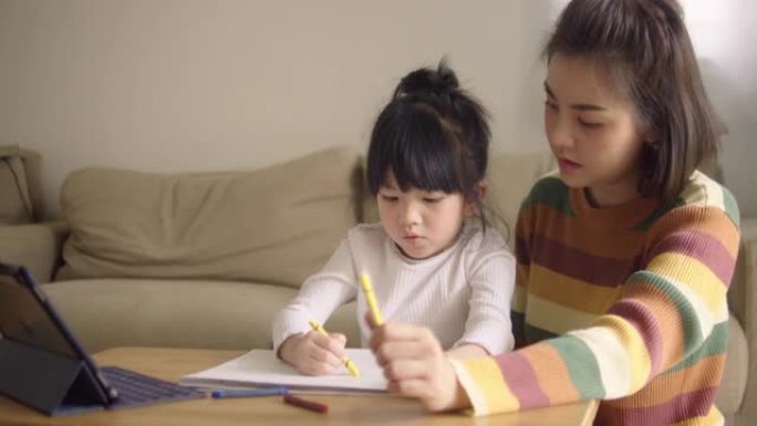 亚裔女儿在家和母亲一起参加网络课程。