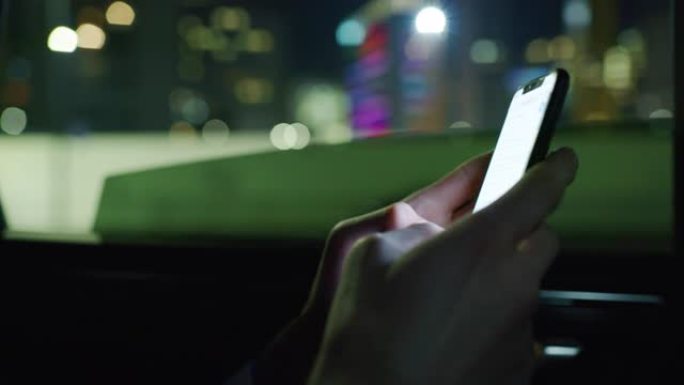 慢动作近距离的商人的手使用手机在一个现代汽车旅行与司机在市中心的夜晚。