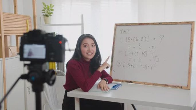 美丽的亚洲女性在线教授数学，微笑的亚洲女性老师在线录制vlog或数学课。
