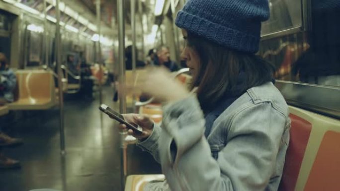 在纽约地铁上使用电话的亚洲妇女