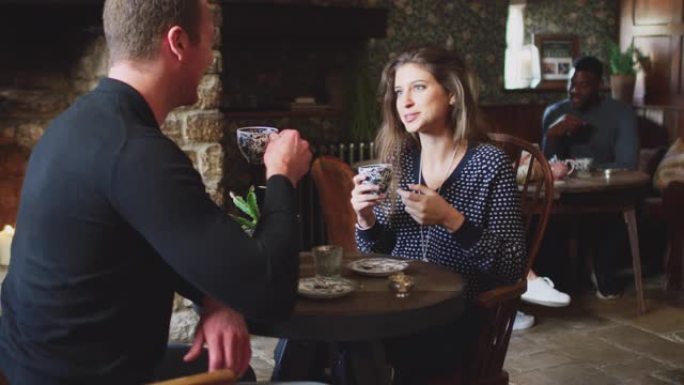 夫妇坐在餐桌旁，在传统的英国度假酒店喝茶-慢动作拍摄