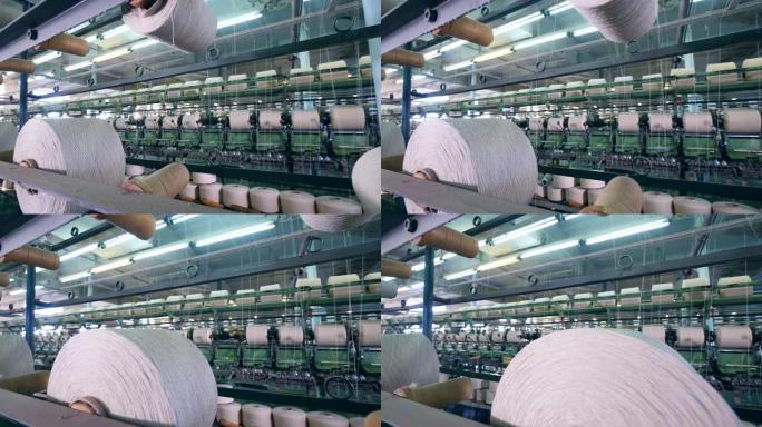 白线在卷轴之间被机械地重新定位。纺织厂设备。