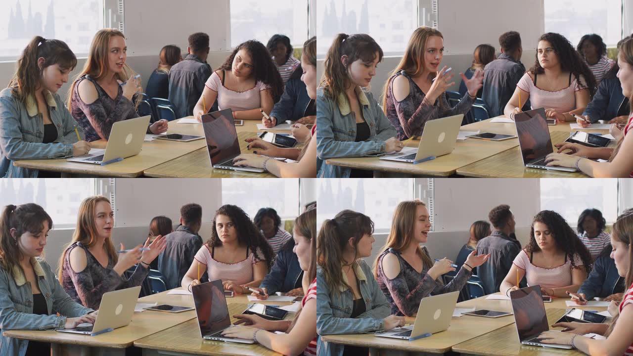 一群使用笔记本电脑坐在办公桌前的女大学生共同参与项目