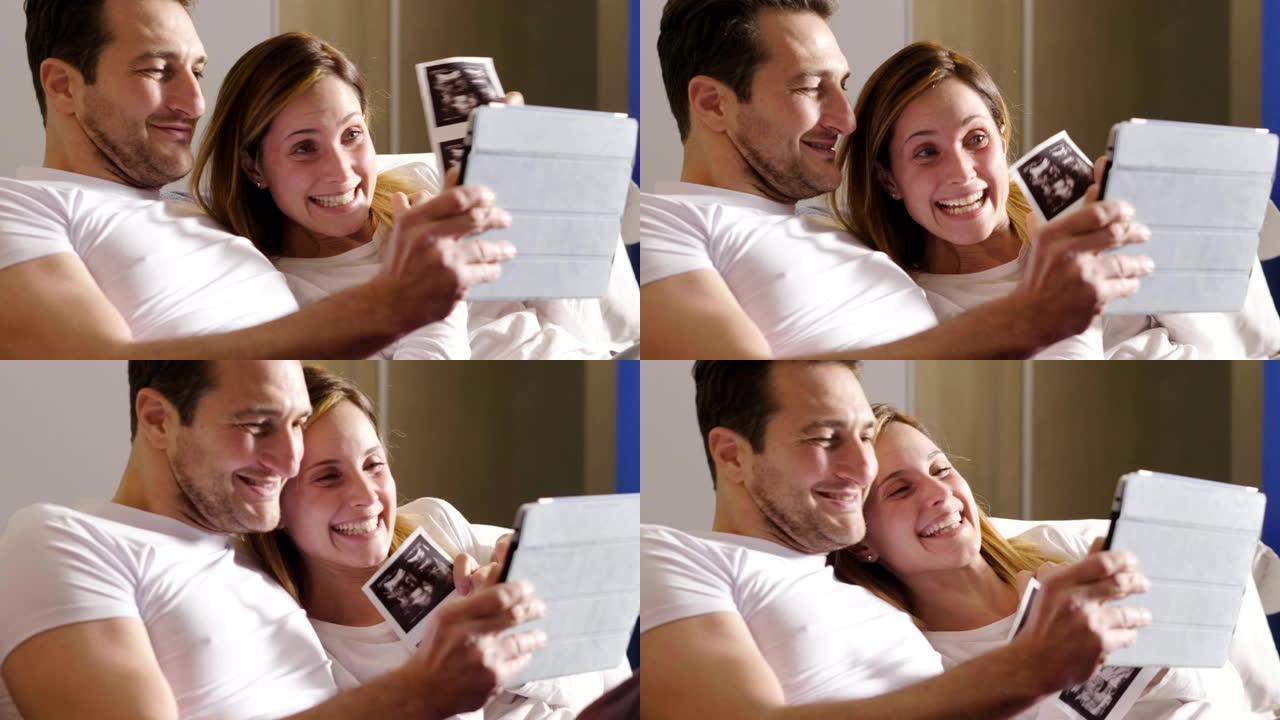 一对恋爱中的已婚夫妇使用平板电脑对父母进行视频拍摄，以宣布儿子的出生显示超声波。