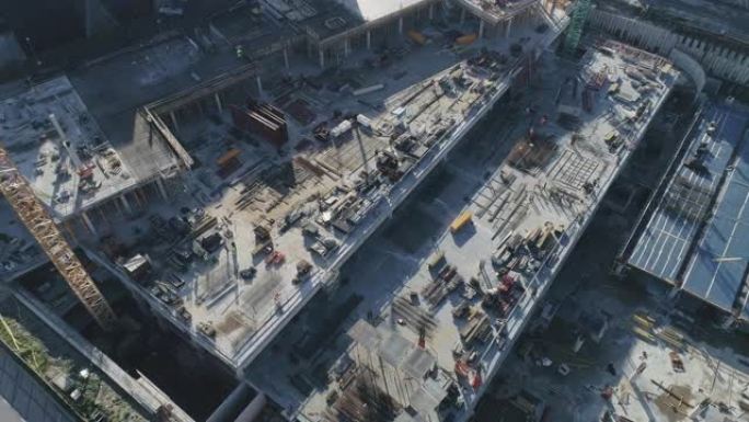 在建造房屋的过程中，一个工业建筑场的空中自上而下的无人机镜头。建筑工人正在现场工作。快节奏。