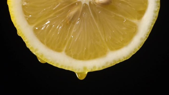 慢动作: 柠檬片上的许多液体掉落在黑色上