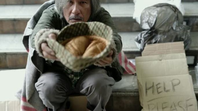 向上倾斜: 无家可归者在人行道上戴着帽子。