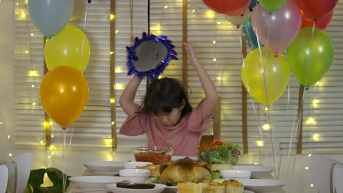 悲伤的亚洲小女孩独自在一张有蛋糕和蜡烛的桌子上庆祝她的生日，客人不来。慢动作。
