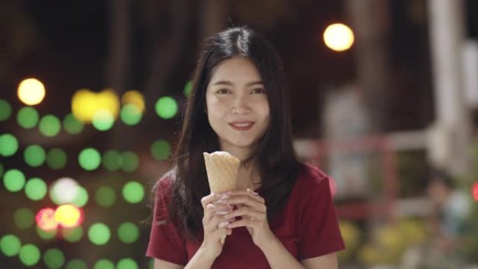 亚洲年轻女子在泰国曼谷旅行，美丽的女性在考山路散步和吃冰淇淋感到快乐。妇女旅游吃街头食品泰国概念。慢