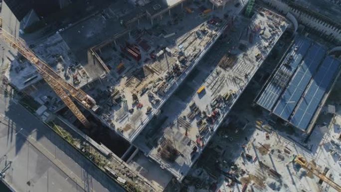 在建造房屋的过程中，一个工业建筑场的空中自上而下的无人机镜头。建筑工人正在现场工作。