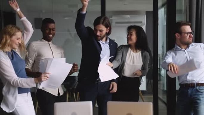 快乐的跨国商业团队人们在办公室跳舞扔论文