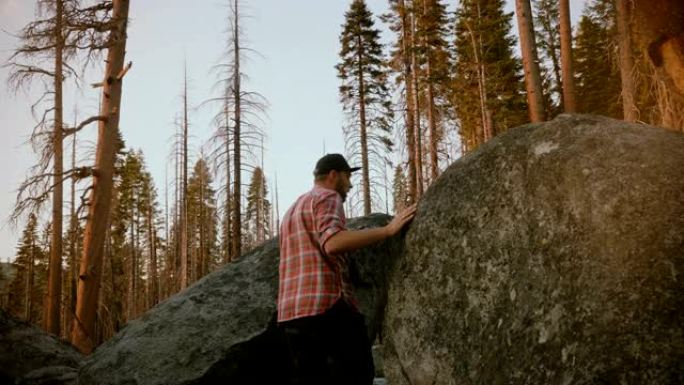 镜头跟随当地一名年轻男子徒步旅行，爬上森林的巨石在优胜美地观看史诗般的日落慢镜头。