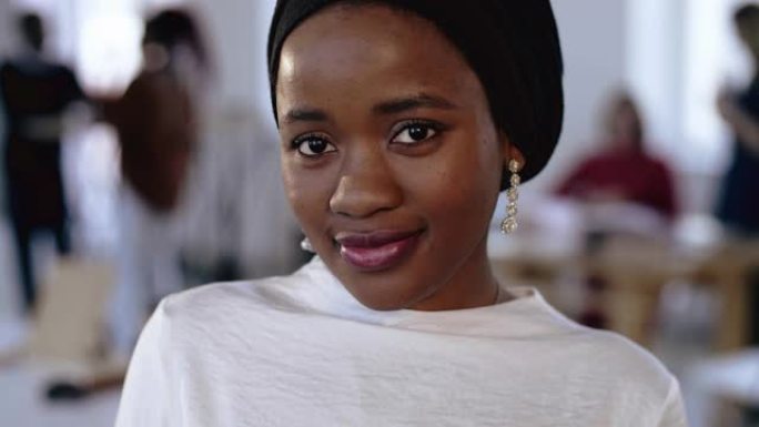 年轻快乐的非洲女商人在少数民族的头巾摆姿势的特写，微笑在现代时尚的办公室。