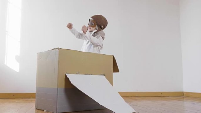 卧室里一个打扮成飞行员或飞行员的女孩假装驾驶纸飞机，并想象自己在天空中自由飞翔。