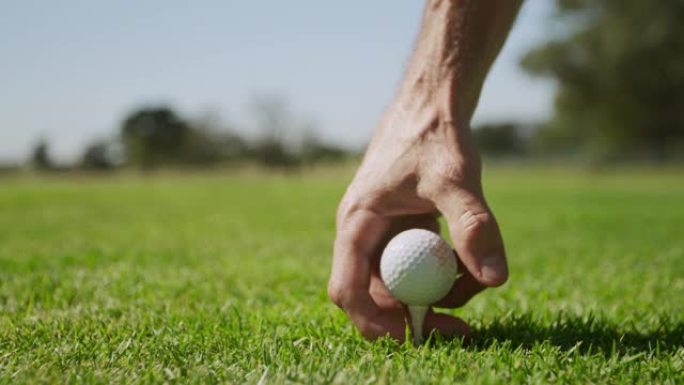 高加索男性高尔夫球手将高尔夫球放在发球台上