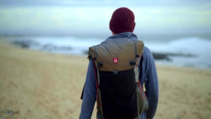 带旅行背包的男孩在海滩上散步