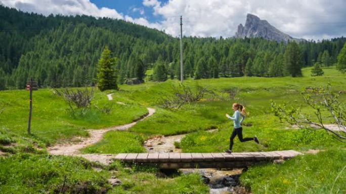 运动女子保持体形，在意大利多洛米蒂山间的绿色景观中奔跑