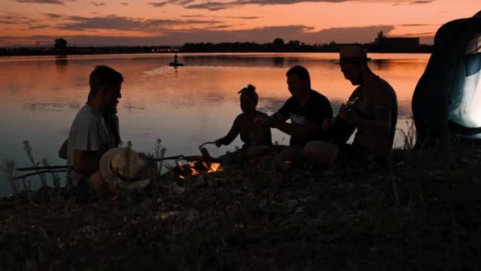 SLO MO一群年轻人在黄昏时在湖边露营