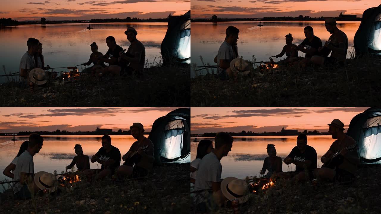 SLO MO一群年轻人在黄昏时在湖边露营